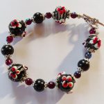 Zwarte armband van handgemaakte glaskralen met rode bloemen