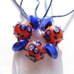 Set van 7 handgemaakte glaskralen in oranje met blauw