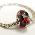 Zwarte lampwork kraal met 3 donkerrode bloemen