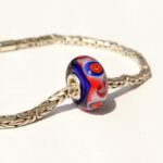 Blauwe glasbedel met roodoranje lijnversiering