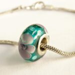 Turquoise glaskraal met paarse bloemen