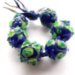 Blauwe glaskralen met groene bloemen