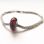 Zwarte glaskraal met rode bloemen